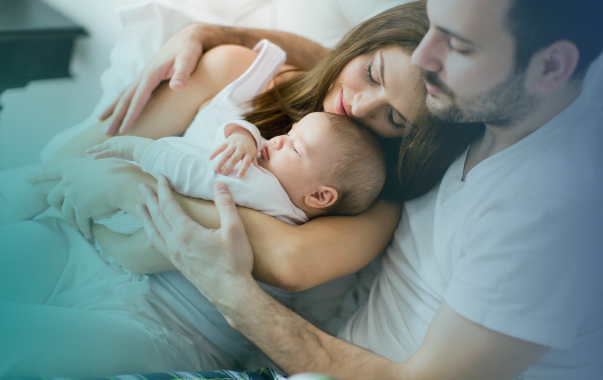 Imagem de um casal feliz segurando um bebê em casa, simbolizando a realização do sonho de ter filhos
