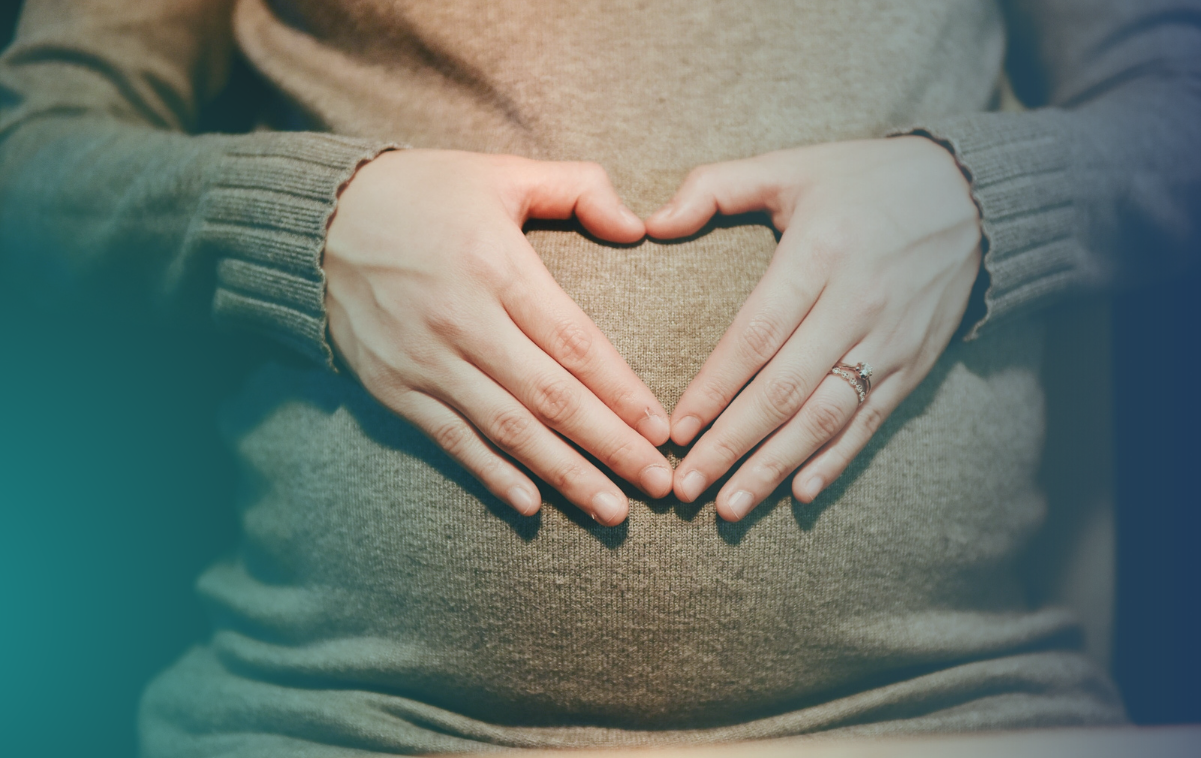 imagem de uma barriga de gestante com as mãos em formato de coração cobrindo a barriga na fase pré-natal para uma gestação saudável e tranquila